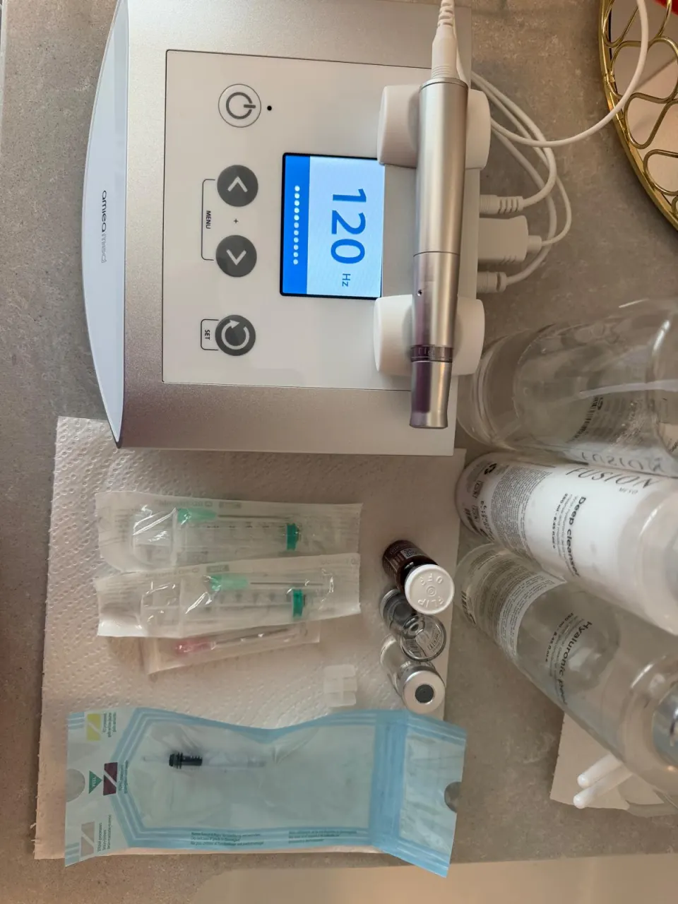 Aparatul de microneedling Exceed pe blat, cu aplicatorul în suport, lângă seringi, fiole și cartușul steril